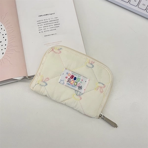 Close-up of quilted cream wallet with colorful stitching and soft zipper texture