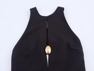 Detail van de zwarte mini-jurk met een elegante goudkleurige metalen ovale gesp