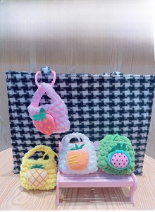 Detailed view of handmade knitted fruit mini pouches including strawberry and pineapple styles