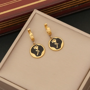 Detailed view of gold hoop earrings with black rose pendants in a beige jewelry box