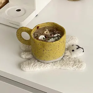 Detailed top view of a yellow spotted ceramic mug on a sheep coaster with latte art decoration