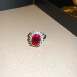 Detailed macro of a silver flower ring with red oval gemstone and zircon accents