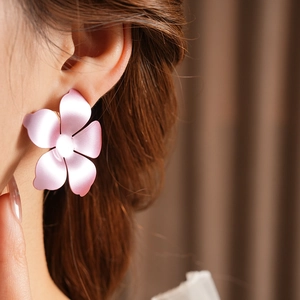 Gros plan d'une boucle d'oreille fleur rose mate avec dégradé portée sur un mannequin
