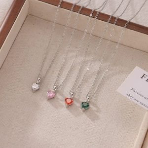 Elegant heart pendant necklaces in four colors displayed on a beige jewelry tray