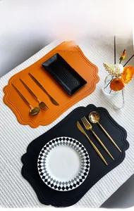 Detail of scalloped edge vintage leather placemats in orange and black for dining decor