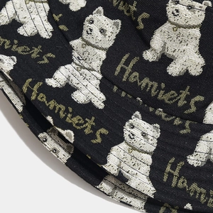 Detailed macro view of black twill bucket hat with white dog pattern and Homiets text