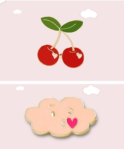 Detail of cute cherry and pink cloud enamel pins with gold metal edges on pink background