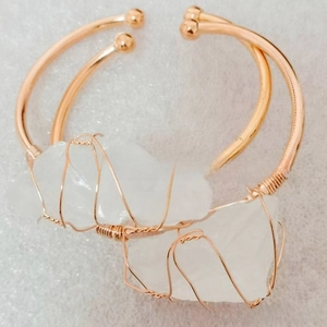 Detail of rose gold wire-wrapped open cuff bracelets with irregular white raw stones