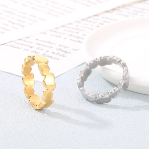 Detail view of heart-shaped hollow rings in gold and silver finishes on a ceramic dish