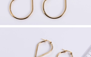 Macro view of gold teardrop-shaped steel earrings showing the hinge and polished finish