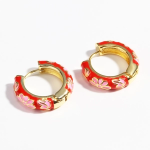 Detail of red enamel hoop earrings with gold trim and pink floral patterns