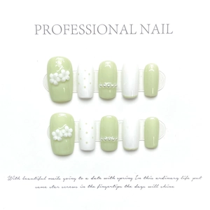 Detail of green and white handmade press-on nails with 3D flowers and pearls