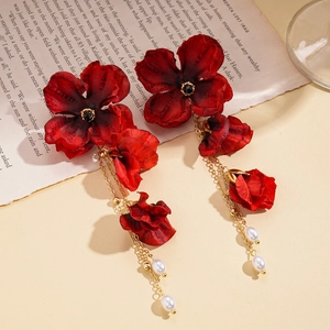 Detailansicht der roten Stoffblumen-Ohrringe mit Goldkette und weißen Perlenquasten