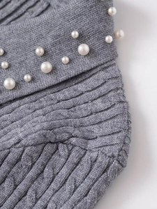 Detailed close-up of grey cable knit texture featuring elegant faux pearl embellishments