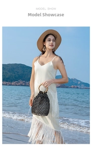 Fashion model showcasing a white fringe maxi dress with a woven bamboo handle bucket bag