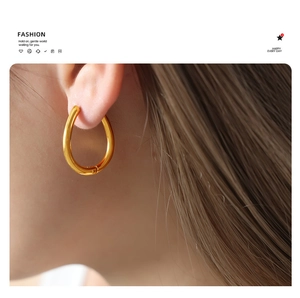 Close-up of golden teardrop metal earrings with elegant shell pearls on a female model