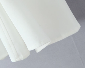 Detail shot of white woven fabric with professional stitching and high-quality hem finishing