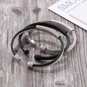 Close-up of industrial stainless steel twisted cable bangles in black and silver finishes
