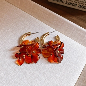 Detail of amber flower earrings with golden metal loops and translucent resin petals