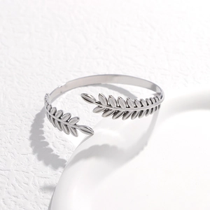 Dettaglio macro della texture a foglia argentata e del motivo a spiga sul bracciale in acciaio