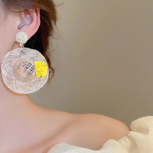 Close-up of woven straw hat floral earring on a model for beach vacation style