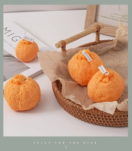 Vela aromática con forma de naranja realista y textura de cáscara en bandeja