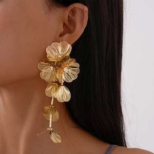 Close-up of a gold mesh petal flower drop earring with rhinestones worn by a model