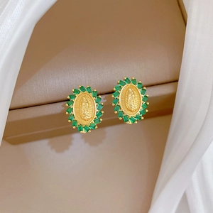 Close-up of vintage gold earrings with oval portrait relief and green baguette stones