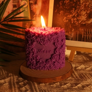 Macro detail of purple cylindrical rose candle with Love heart carving on wood base