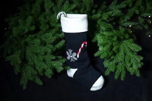 Detailed view of black knitted Christmas stocking featuring white snowflake and candy cane patterns