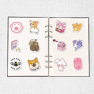 Flat lay of 12 cute waterproof cartoon stickers on a white notebook for DIY decoration