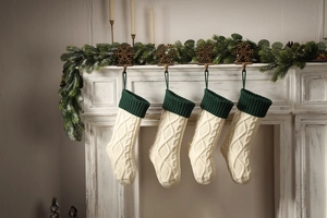 Close-up of four knitted Christmas stockings with cream body and dark green cuffs