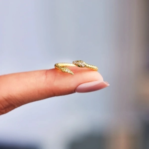 Detail of gold snake ring featuring green gemstone eyes and sparkling white zircon pavé