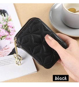 Detail of black star-quilted leather mini pouch with gold zipper and keychain hook