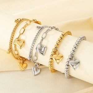 Detail view of 18K gold and silver layered heart charm bracelets with polished steel beads