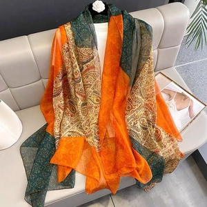 Detail of bohemian chiffon scarf with orange and green paisley patterns on a hanger