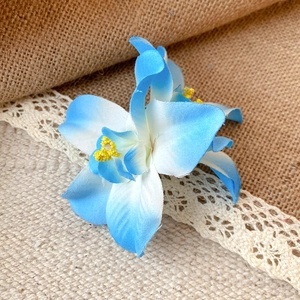 Vue détaillée d'une épingle à cheveux fleur en tissu bleu dégradé sur dentelle.