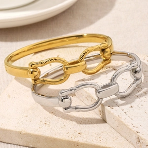 Modern 18K gold and silver double ring chain bracelets on a textured stone display