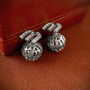 Vue macro de boucles d oreilles argentées lettre m avec cristaux de zircon blancs