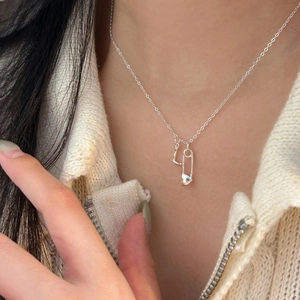 Minimalist 925 sterling silver necklace with heart and safety pin pendant on model
