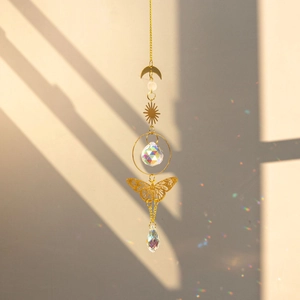 Detail view of brass butterfly suncatcher reflecting rainbow light spots on beige wall
