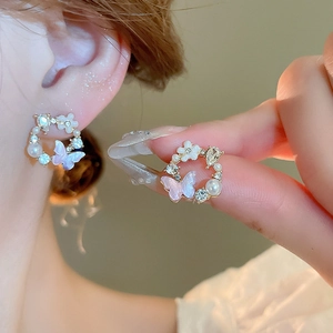 Detail of floral butterfly stud earrings with pearls and crystals on a light gold base