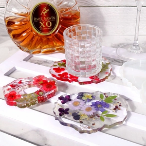 Detail of DIY silicone molds and finished resin coasters with dried flowers and wavy edges