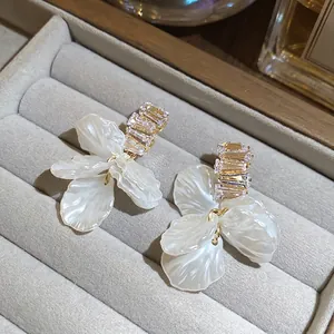 Elegant gold-plated shell flower earrings with crystal accents in a velvet jewelry box