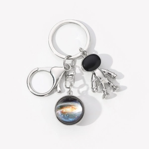 Detail of silver astronaut keychain with galaxy glass pendant on a white background