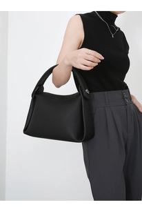 Detail of black pebbled leather texture and silver hardware on a large tote handbag