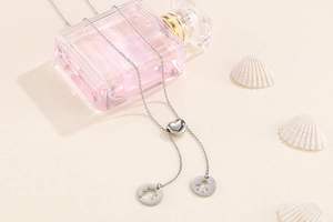 Détail du collier coeur argenté avec pendentifs silhouettes de garçon et fille ajourés