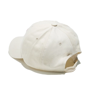 Detail view of cream cotton baseball cap showing adjustable strap and metal buckle