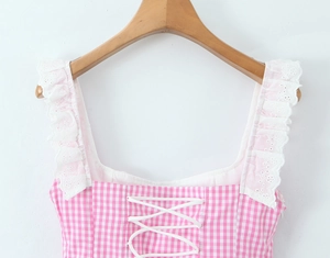 Detail of pink plaid top featuring delicate white lace straps and corset tie-up front