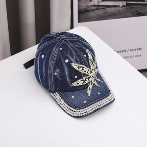 Detail of rhinestone and pearl leaf patterns on a dark blue washed denim baseball cap